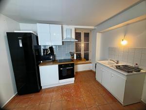 ブレ・シュル・セーヌにあるL'Authentique de la Brieの白いキャビネットと黒い冷蔵庫のあるキッチン