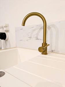 a kitchen sink with a gold faucet at Tiny House moderne et cosy in Vernouillet
