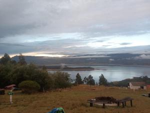 a bench in a field with a view of a lake at Zona de camping zoe in Guatavita