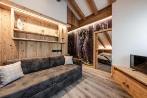 Una sala de estar con un sofá y un televisor. en Suite Illuminata con piccolo centro wellness, en Commezzadura