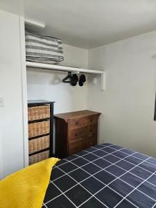 a bedroom with a bed and a wooden dresser at Marg's on the Corner in Kumara