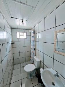 a white bathroom with a toilet and a sink at Cantinho da Nonna in Morretes