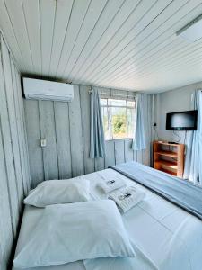 a bedroom with a large white bed with a window at Cantinho da Nonna in Morretes +10 photos