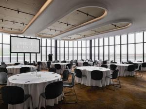 a room with white tables and chairs and windows at Hotel Chadstone Melbourne MGallery Collection in Chadstone +180 photos