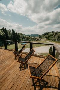 a deck with two chairs and a table on it at Rezidence Rokytnice in Rokytnice nad Jizerou