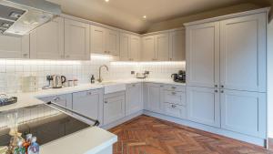 a white kitchen with white cabinets and a wooden floor at Ramsbury Cottage in Ramsbury