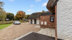 a brick house with a car parked in the driveway at Ramsbury Cottage in Ramsbury