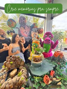 a group of people standing around a table with a display of food at Hotel Recanto dos Dinossauros in Penha