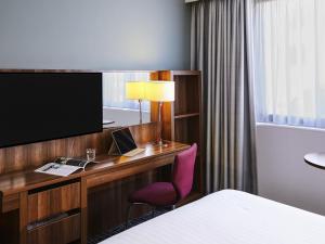 a hotel room with a desk with a computer and a tv at Mercure Telford Centre Hotel in Telford