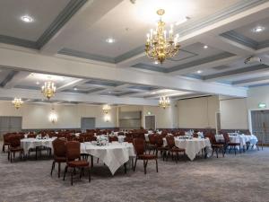 a banquet hall with white tables and chairs and chandeliers at Mercure Barnsley Tankersley Manor Hotel in Barnsley