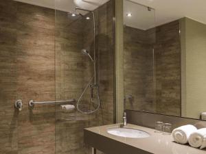 a bathroom with a shower with a sink and a mirror at Mercure Concepcion in Concepción