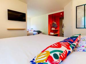 a bedroom with a white bed with a colorful pillow at greet Hotel Beaune in Beaune