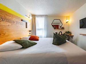 een slaapkamer met een bed met twee kussens erop bij greet Hotel Beaune in Beaune +138 foto's