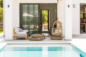 a patio with a pool and chairs and a house at Elegante Villa Mit Beheiztem Pool Und Fantastischer Aussicht in Skouloúfia