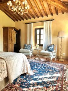 a bedroom with a bed and two chairs and a rug at Agriturismo La Frattina in Buonconvento