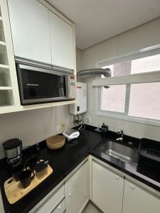 eine Küche mit Spüle und Mikrowelle in der Unterkunft Melhor apartamento de capão! 100m da praia in Capão da Canoa