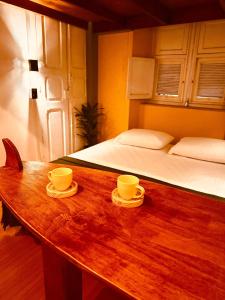 una stanza con un tavolo di legno con due tazze e un letto di Cocos Hostel Rio a Rio de Janeiro