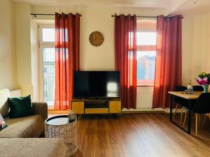 ein Wohnzimmer mit einem TV und roten Vorhängen in der Unterkunft Apartament Ratuszowy in Wałbrzych
