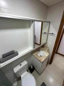 ein Badezimmer mit Toilette, Waschbecken und Spiegel in der Unterkunft Melhor apartamento de capão! 100m da praia in Capão da Canoa