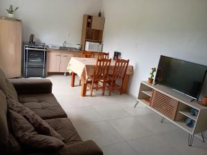 a living room with a couch and a table with a television at Casa com visto para o Cristo e cidade in Encantado +12 photos