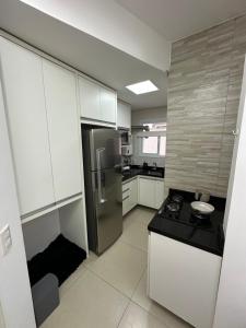 eine Küche mit weißen Schränken und einem Edelstahlkühlschrank in der Unterkunft Melhor apartamento de capão! 100m da praia in Capão da Canoa