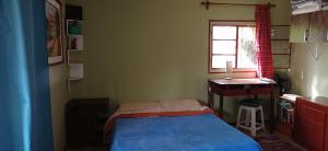 ein Schlafzimmer mit Bett, Schreibtisch und Fenster in der Unterkunft Puka ra in Colonia del Sacramento