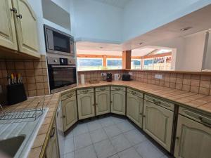 a large kitchen with wooden cabinets and a large window at Gîte Horizons Landais Séjour professionnel et vacances dans les Landes in Pontonx-sur-lʼAdour
