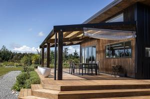 a house with a wooden deck with a table on it at Halcyon Point in Hokitika Airport