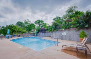 a swimming pool with two chairs next to a wall at Tiki Time-2BD2BAPoolsGrillPatio-Four Seasons in Lake Ozark