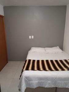 a bed with a striped blanket on it in a room at Casa com visto para o Cristo e cidade in Encantado