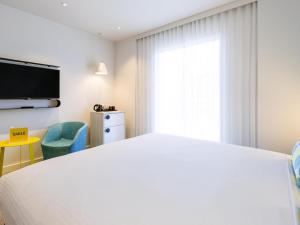 パースにあるibis Styles East Perthの大きな白いベッドと窓のある寝室