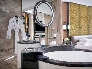 a bathroom with a large tub and a mirror at Sofitel Beijing Central in Beijing