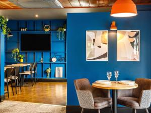 a dining room with blue walls and a table and chairs at ibis Wakefield East-Castleford in Wakefield