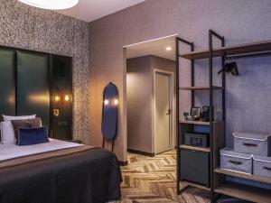 a bedroom with a bed and a large mirror at Mercure Figeac Viguier du Roy in Figeac