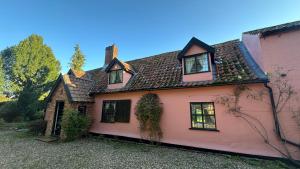 ein rosa Haus mit einem braunen Dach in der Unterkunft Danegelts Waveney Marshes Bed & Breakfast in Geldeston