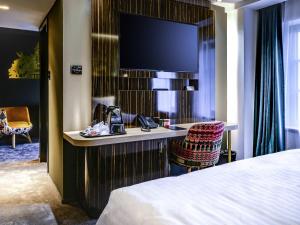 a hotel room with a bed and a desk with a television at Mercure Timisoara in Timişoara