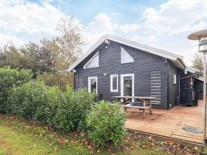 una casa negra con una mesa de picnic en una terraza en 4 star holiday home in Væggerløse, en Bøtø By