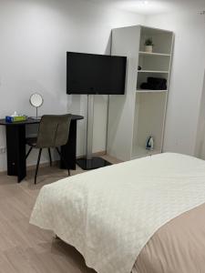 a bedroom with a bed and a desk and a flat screen tv at Chambre Élégance et confort a Esch in Esch-sur-Alzette