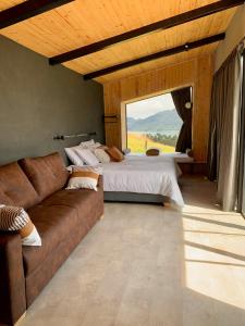 een slaapkamer met een bank en een bed met een raam bij Fuga Neusa in Tausa Viejo