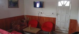 a living room with two red chairs and a tv at El Shaddai Hospedaje Temporal in Santiago del Estero