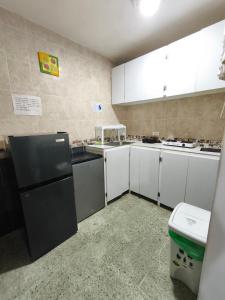 een keuken met witte kasten en een zwarte koelkast bij Emily place 1 y 2 in San Andrés