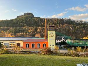 a building with a clock tower in front of a mountain at LilienNest - Stilvolles Apartment mit Panoramablick in Königstein an der Elbe