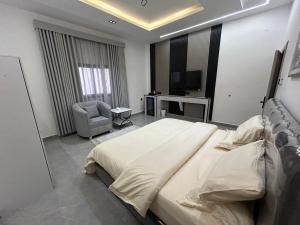 a bedroom with a large white bed and a chair at قمرة قباء Quba moon3 in Al Madinah