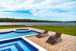 two chairs and a swimming pool next to a body of water at Hotel Via Do Sol Eco Chalés in Trairi