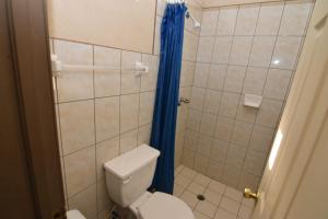 a bathroom with a toilet and a blue shower curtain at San Felipe Rental Studio 3 FREE WIFI AND CABLE TV in San Felipe
