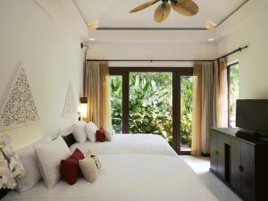a bedroom with two beds and a large window at Mövenpick Asara Resort & Spa Hua Hin in Hua Hin