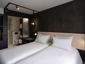 a bedroom with two white beds and a bathroom at TRIBE Paris Batignolles in Paris
