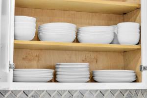 a cupboard filled with white bowls and plates at Chicago Gem! Centrally Located - proximity to O' Hare Airport in Schaumburg