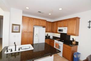 a kitchen with wooden cabinets and a white refrigerator at El Dorado Ranch Vacation Rental Condo 25-1 | 18-Hole Golf in Playa El Paraíso
