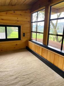an empty room with windows in a log cabin at Casa del Árbol Sesquile in Tres Esquinas